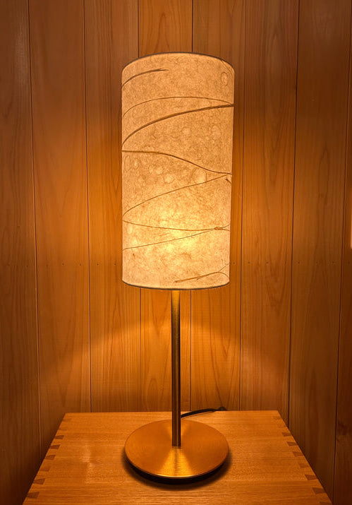 Table lamp with a cylindrical washi shade on a wooden surface.