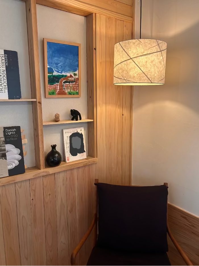 Wooden shelf with decorative items and a washi lamp in a room setting.