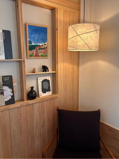 Wooden shelf with decorative items and a washi lamp in a room setting.
