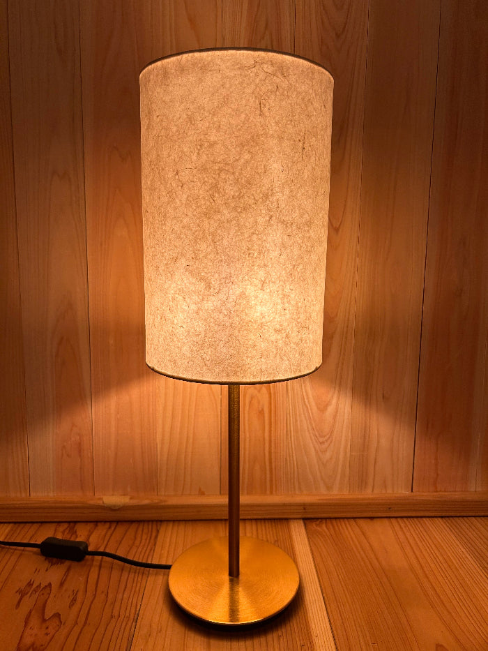 Floor lamp with a cylindrical beige shade on a wooden floor