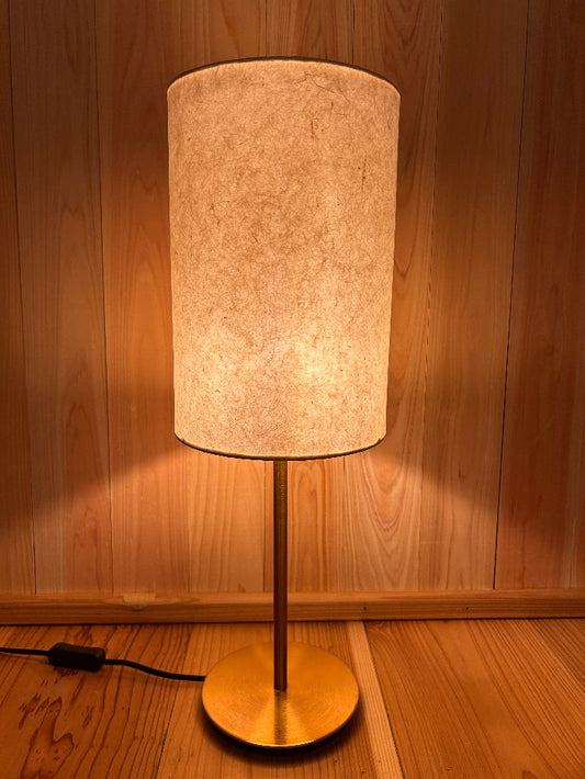 Floor lamp with a cylindrical beige shade on a wooden floor