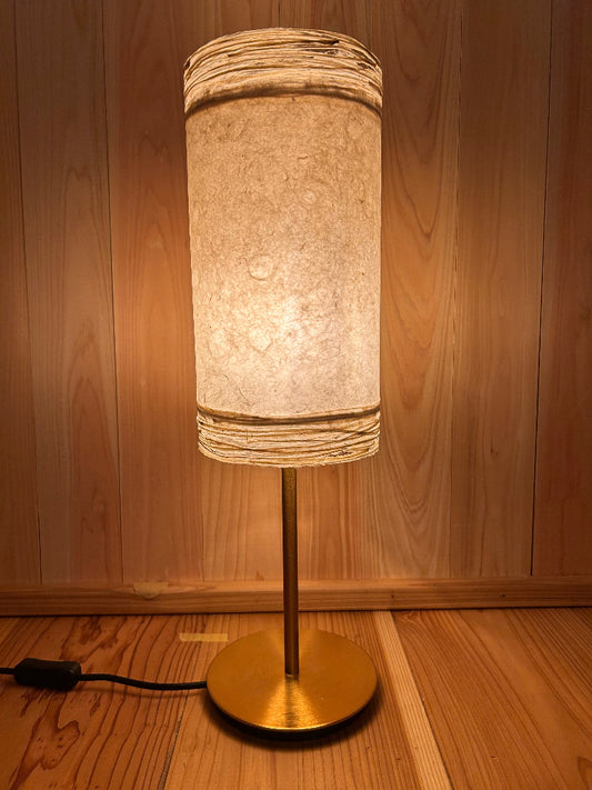 Decorative lamp with a textured shade and gold base on a wooden surface