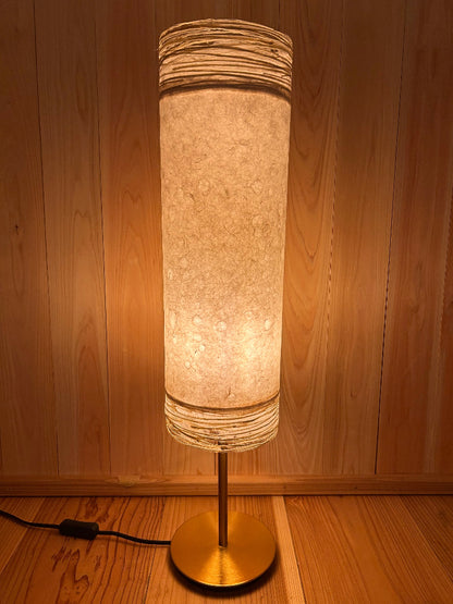 cylindrical lamp with textured shade on a wooden wall