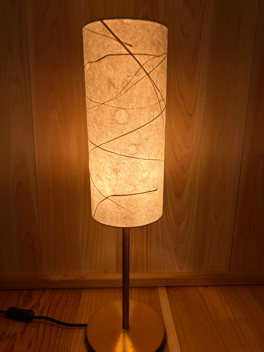 Floor lamp with a cylindrical paper shade with warm glow