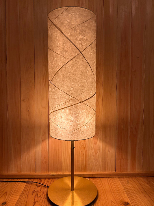 Floor lamp with a textured washi shade on a wooden floor, soft warm light