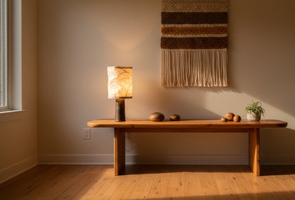 Lamp with a textured white shade on a wooden surface against a wooden wall.