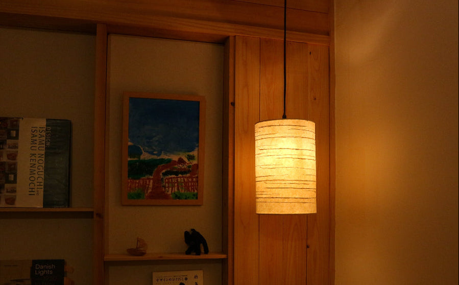 handmade washi pendant light casts soft glow in the corner of a room