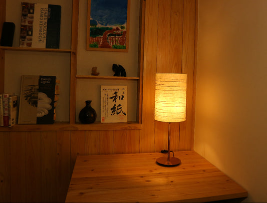 Handmade washi table lamp in a corner casts a soft glow 